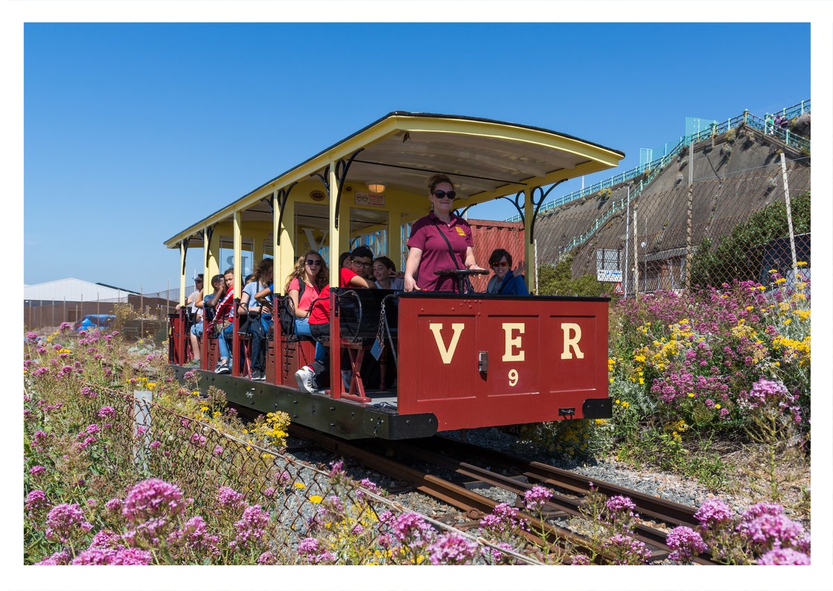 People inside a red carriages with yellow letters VER on the front