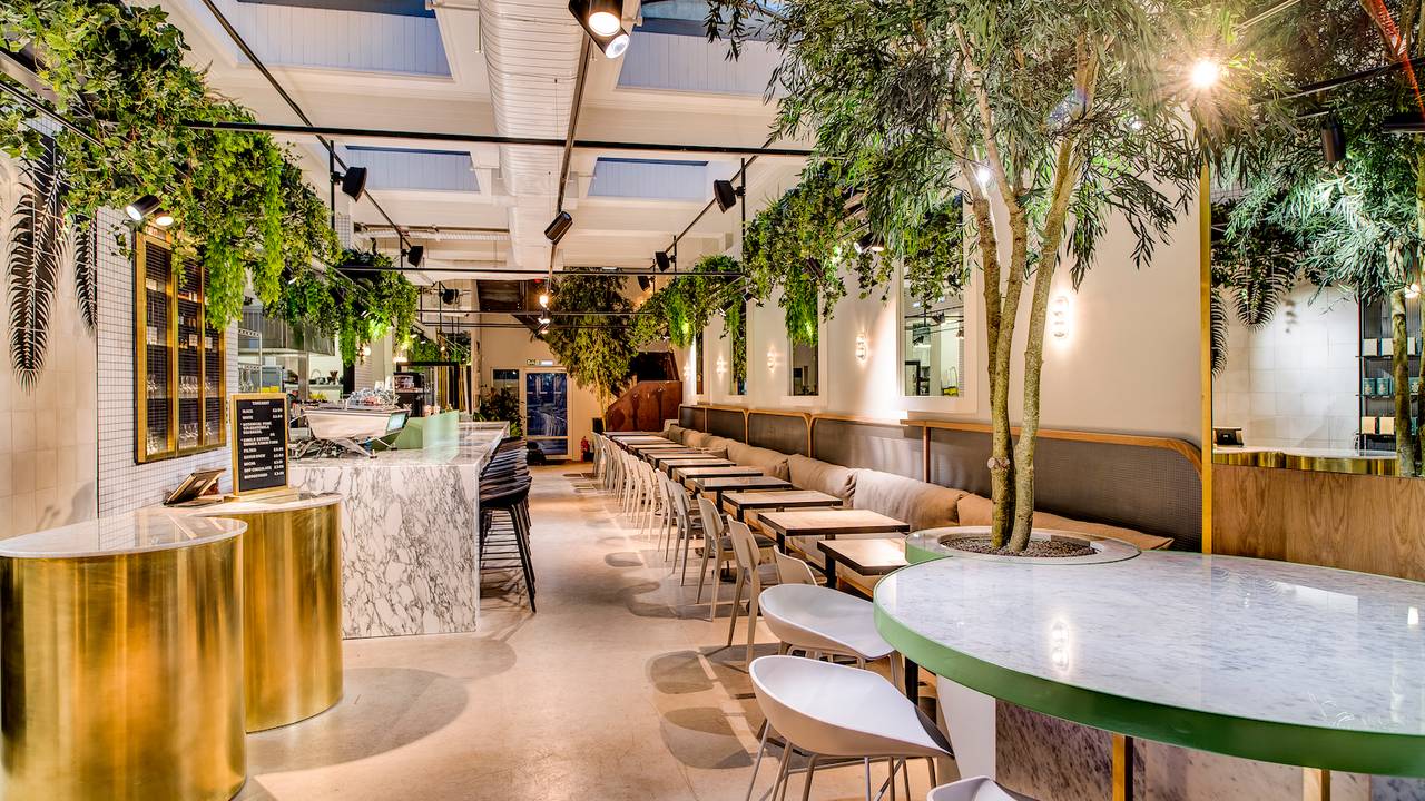 restaurant interior with plants, marble counters, golden elements and tables