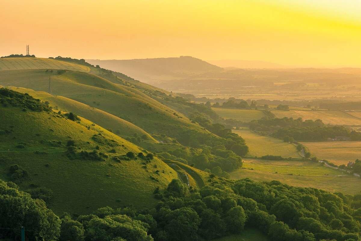 Green hills below a yellow sunset