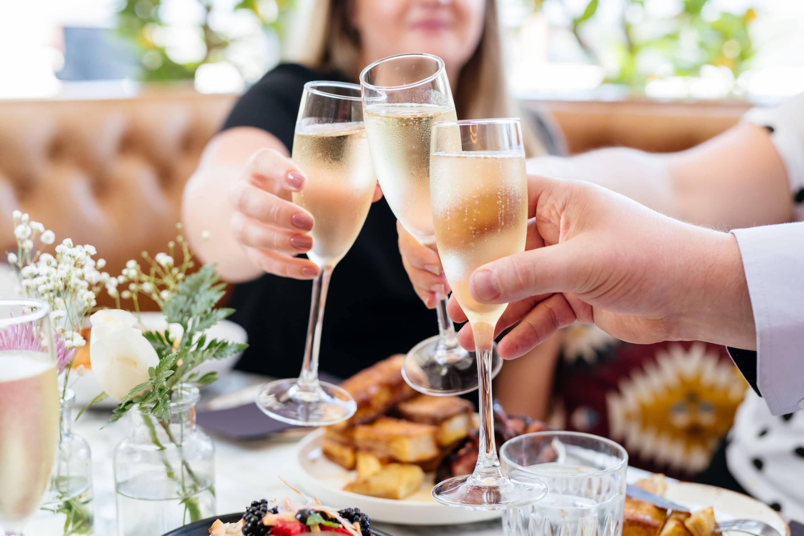 three people touching throwing toast with prosecco glasses