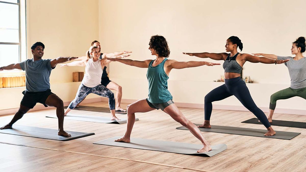 group of people performing warrior one (arms in a T post while in a lunge) position on yoga mats
