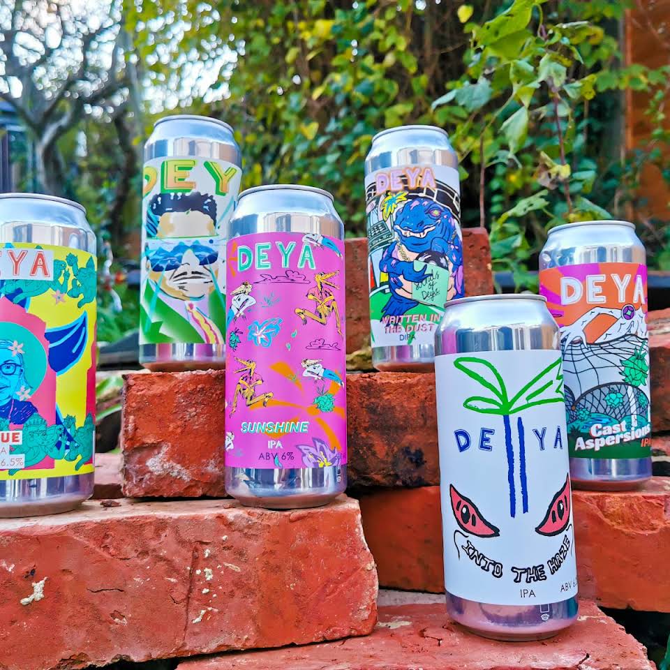 A few cans of beers with different colourful designs, all set up on a few red bricks.