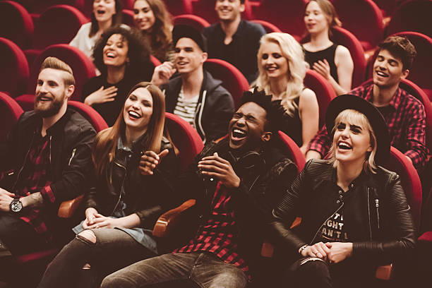 Group of people sitting on red seats and laughing.