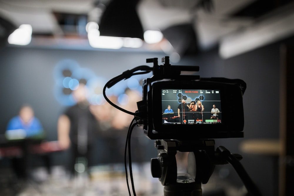 a camera set up filming a a group of people on a black background