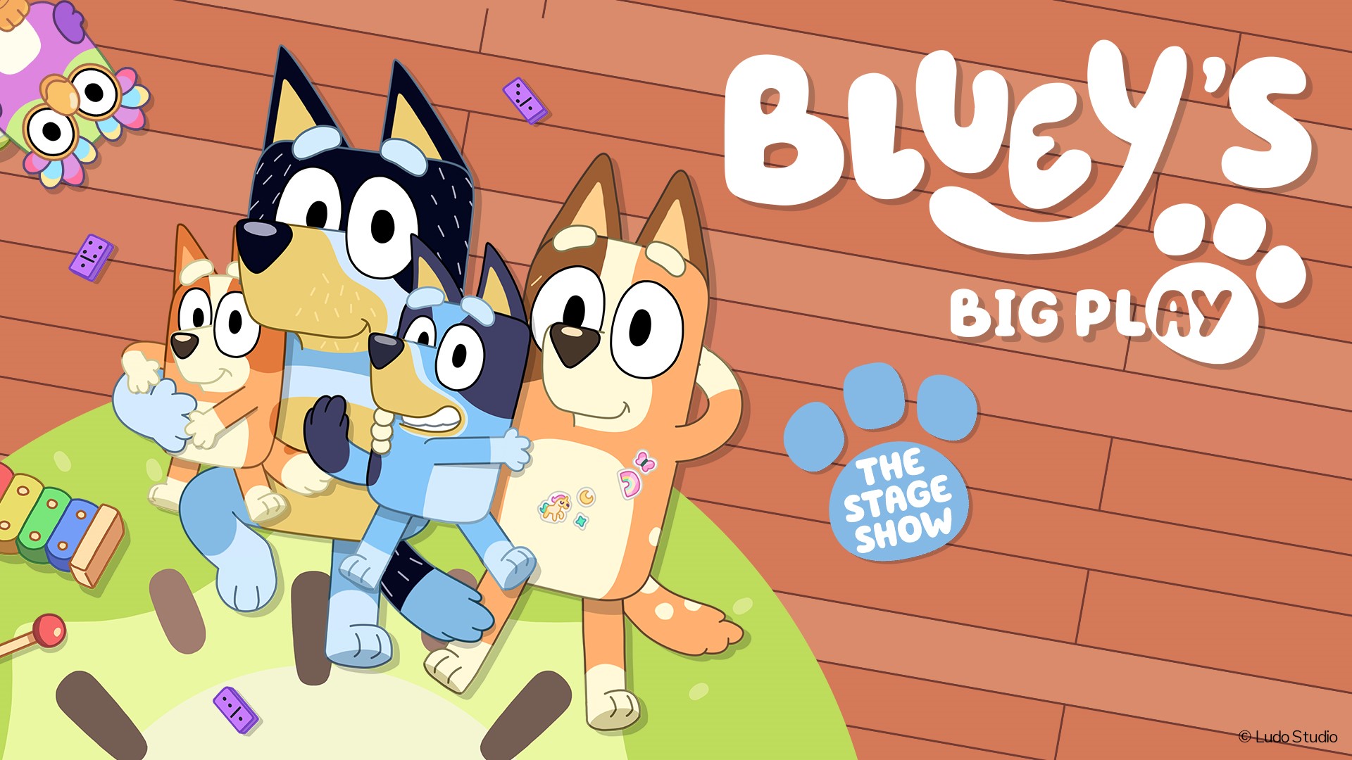 A poster featuring the text "Bluey's Big Play - The Stage Show" and cartoon images of dogs and an owl laying on the a green carpet on a wooden floor.