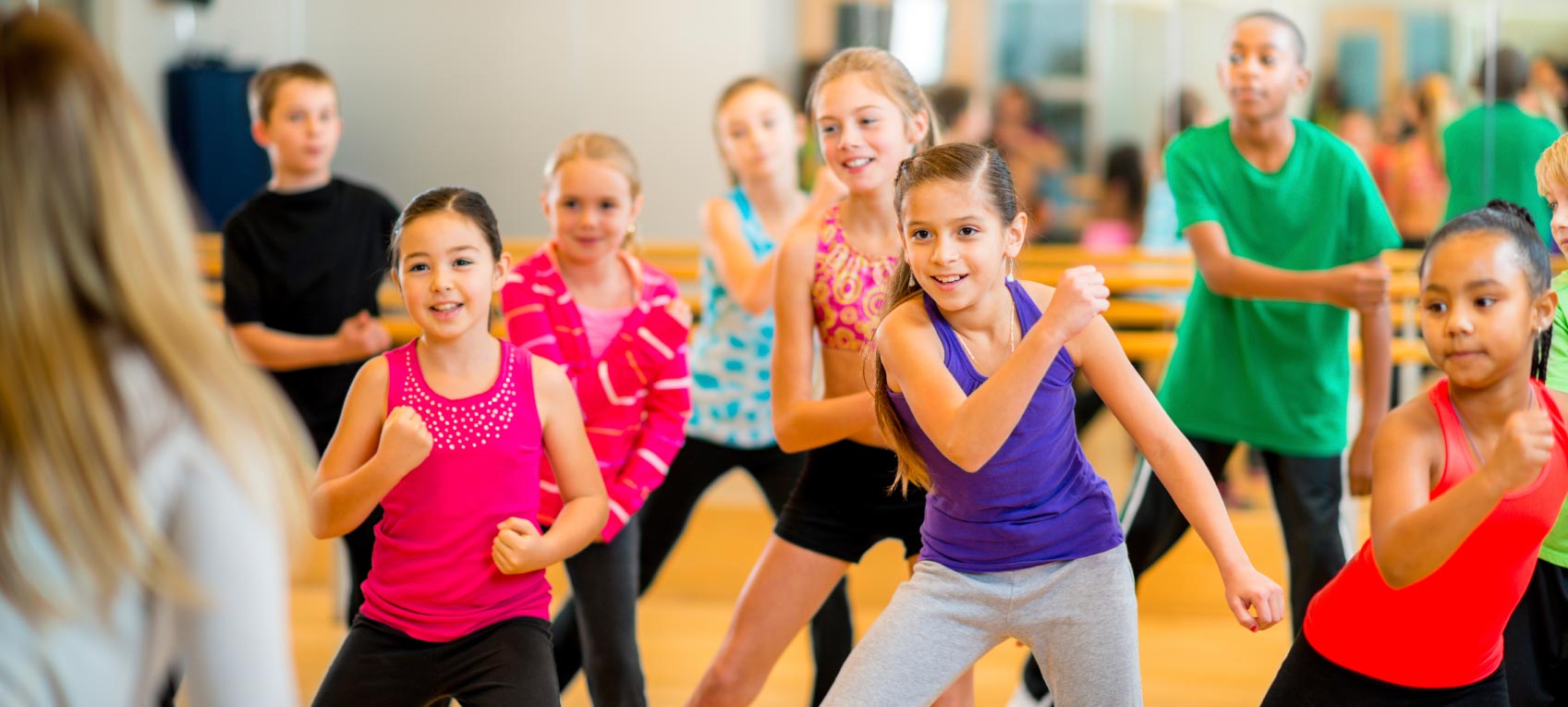 A group of children dressed in different coloured clothes dancing.