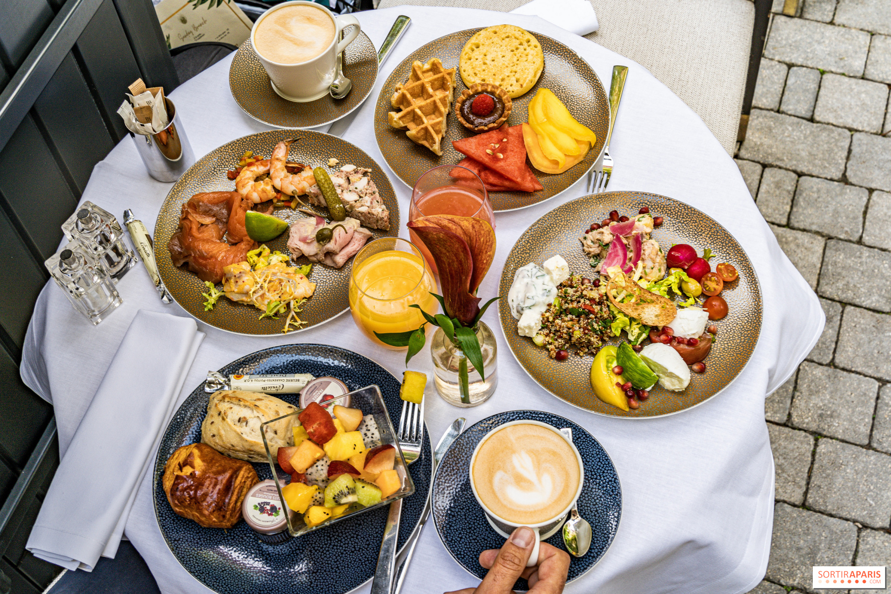 Table set with plates filled with breakfast items and few cups with different drinks.