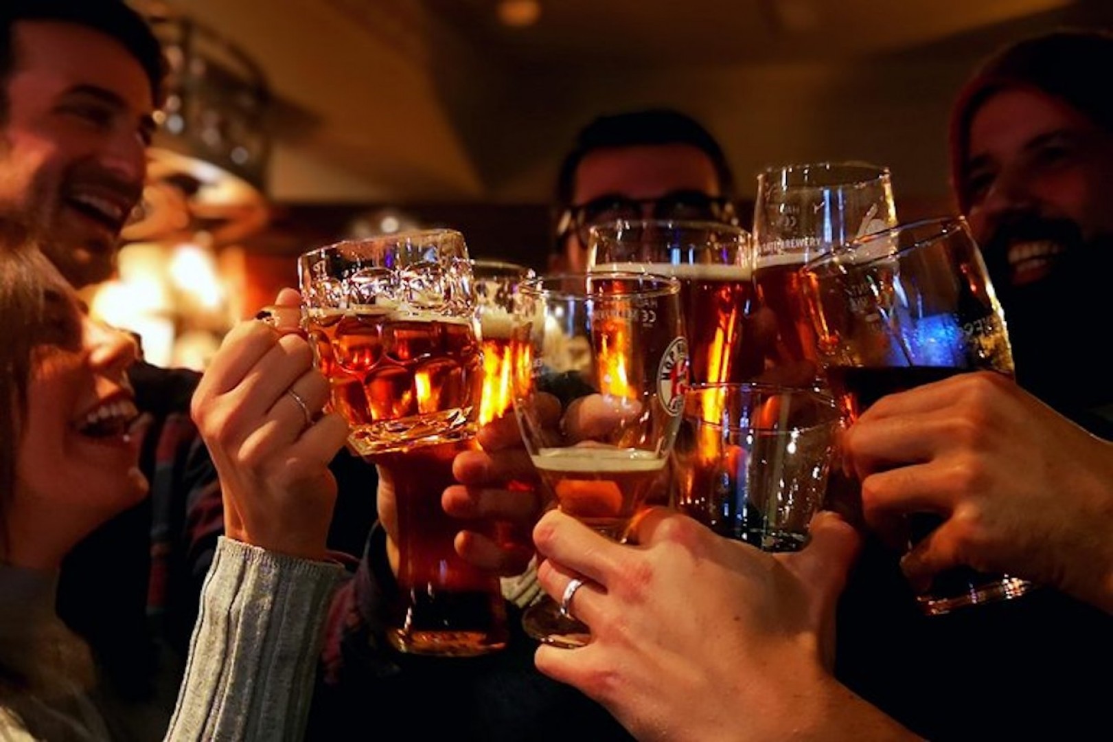 Group of people knocking together glasses full of bear