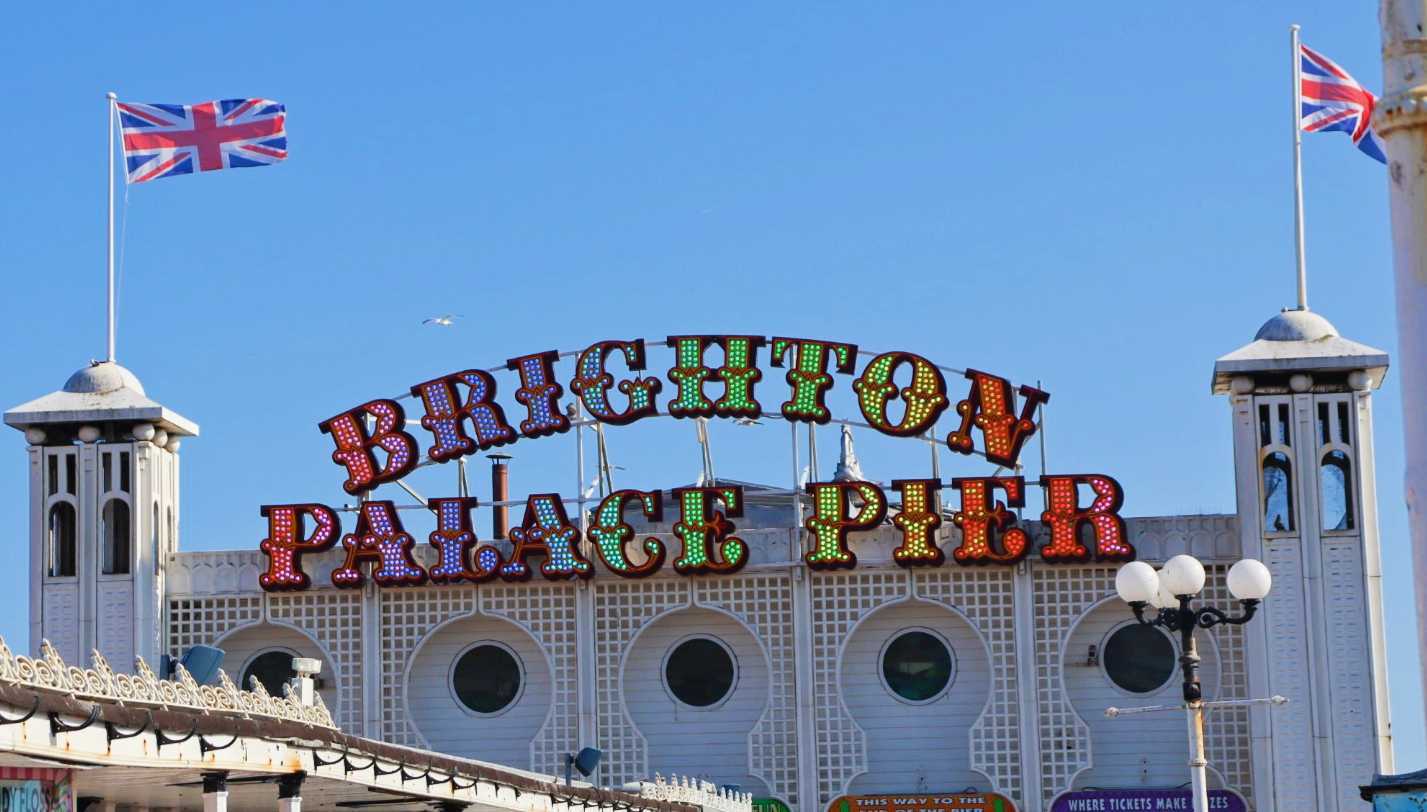 White building with red, white and blue UK flags and a "Brighton Palace Pier" sign