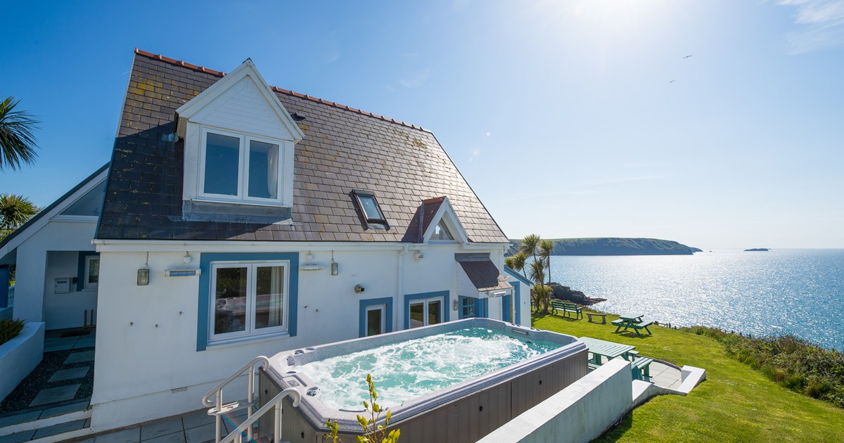 white house with a hot tub outside and a sea view