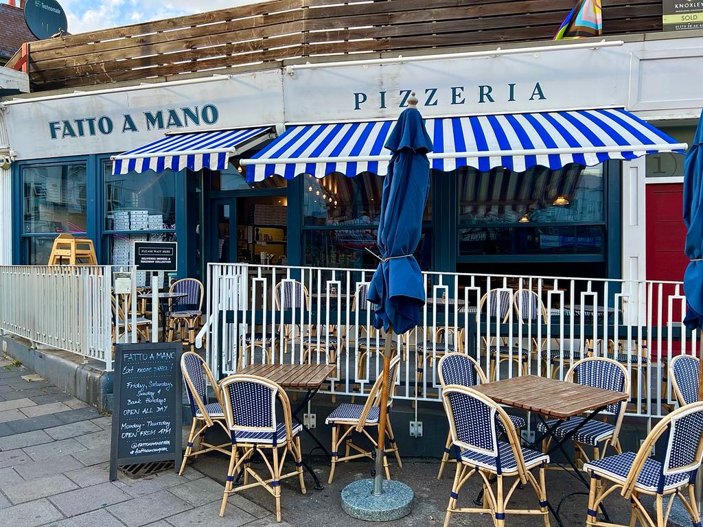 exterior of restaurant with wooden chairs and tables and blue elements to decorate including umbrella
