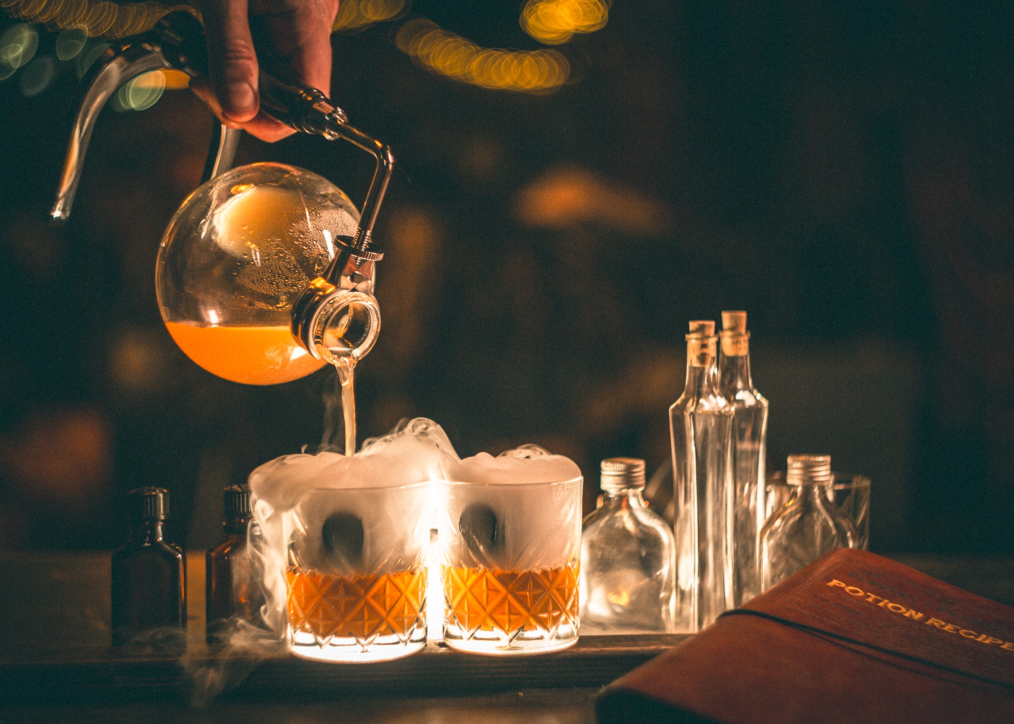 yellow liquid being poured into glasses with smoke coming out