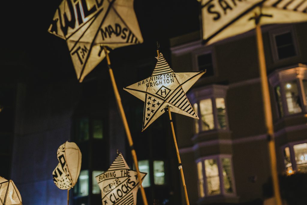 people walking through city centre with lanterns in celebration of burning of the clocks in Brighton.